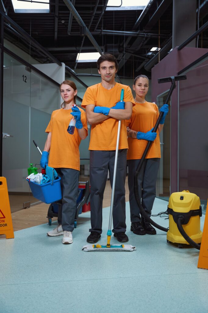 Cleaning company workers holding necessary housecleaning equipment